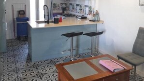 Uma cozinha com ilha central, banquetas, mesa de jantar e uma cadeira.