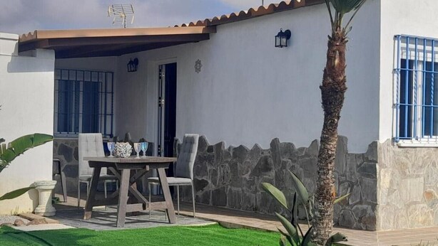 Uma casa com varanda, piscina e muro de pedra.