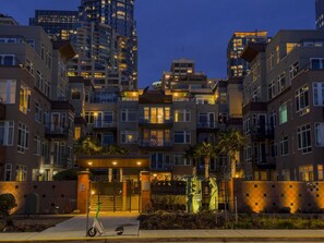 A multi-story residential building with balconies, a gated entrance, and a parking area.