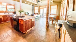 A spacious kitchen with a central island, wooden cabinetry, and a large dining area with a high ceiling and natural light. - Unique Cypress cottage, close to Charlottesville with mountain views. (Charlottesville)