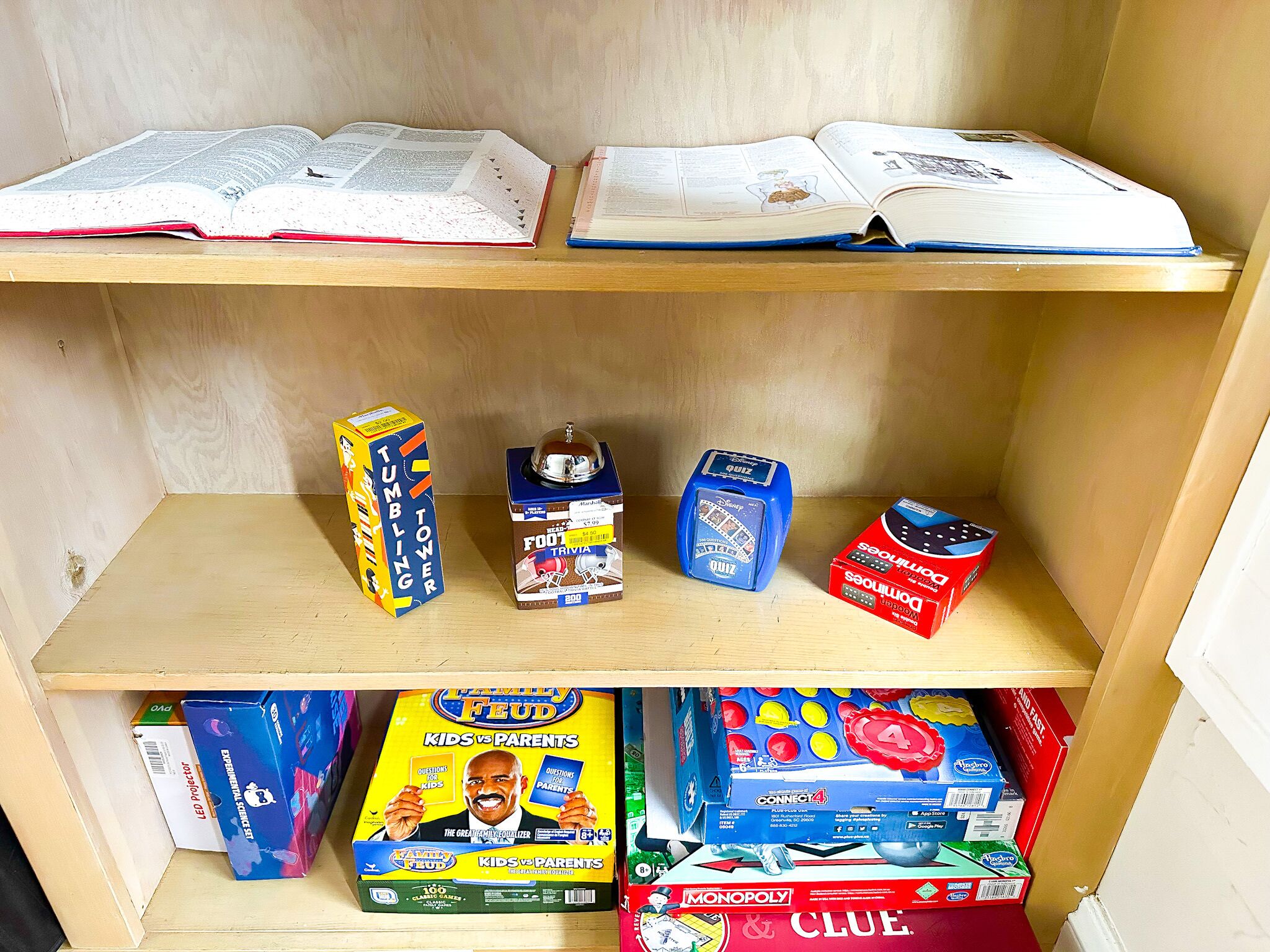 A shelf with books, a trivia game, and a Monopoly game.
