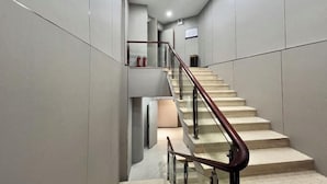 A modern staircase with glass railings and a metal handrail, leading to a landing with a fire extinguisher. - Fengyuanju Business Hotel (Zhongshan)