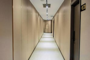 A hotel hallway with a carpeted floor, doors on the right, and a sign above the doors. - Fengyuanju Business Hotel (Zhongshan)