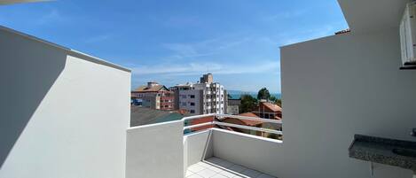 Un balcone con pavimento piastrellato di bianco, una sedia e vista su edifici sullo sfondo.