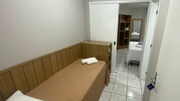 Una habitación pequeña con cama individual, cabecera de madera, mesita de noche y armario.