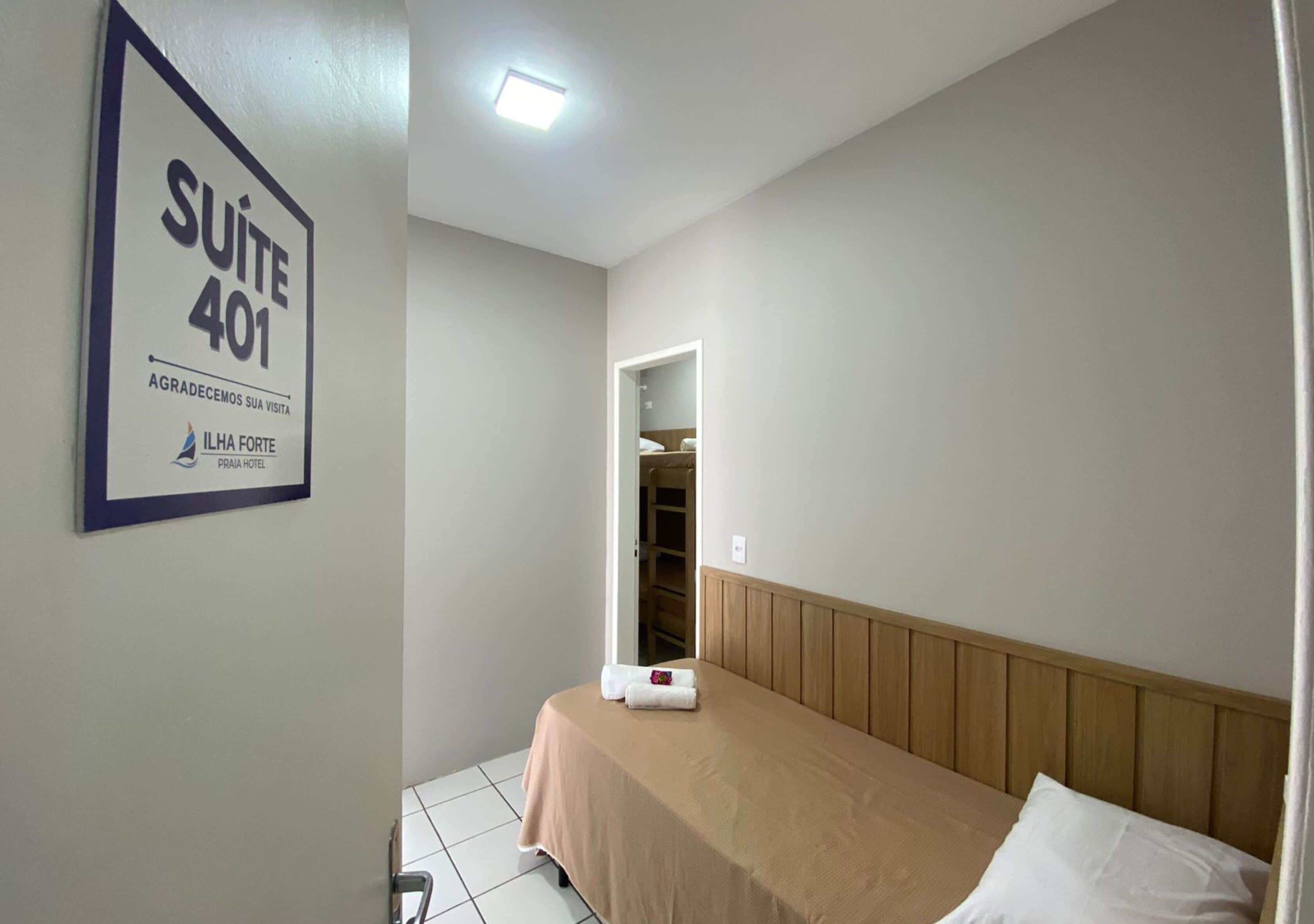 Una habitación de hotel con cama, cabecera de madera, armario y un letrero que indica la Suite 401.
