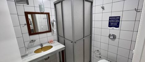 A bathroom with a sink, mirror, toilet, and a shower enclosure.