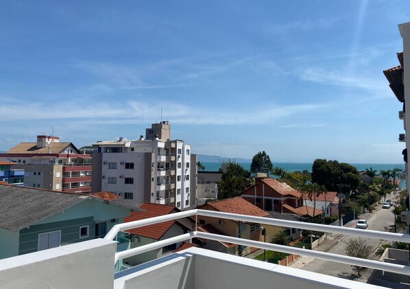 Una zona residencial con vista al mar, con edificios de varios pisos y balcones, bajo un cielo despejado.