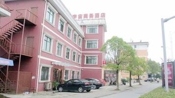 Un edificio de varios pisos con fachada roja, una escalera visible a la izquierda y un letrero que indica un hotel.