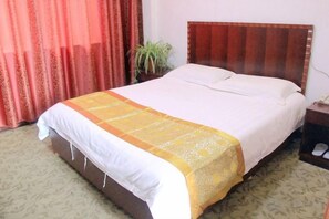 A hotel room with a bed, a nightstand, a telephone, and a plant. - Yuzhou Business Hotel (Nantong)