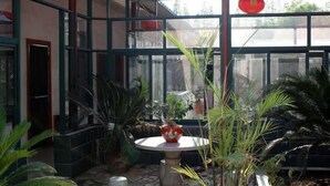 Een oranjerie met een glazen dak, plantenpotten en een rode lantaarn.