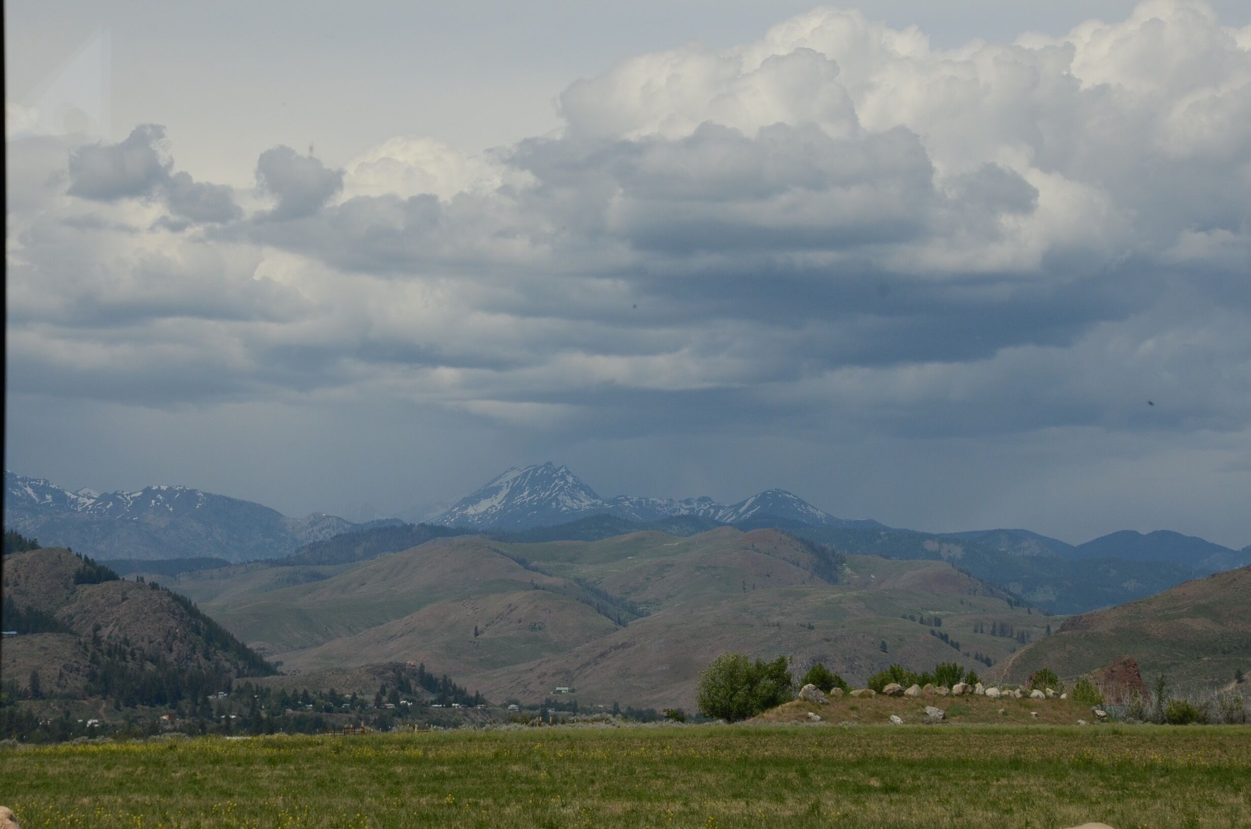 Un paisaje montañoso con colinas ondulantes y un pico lejano.
