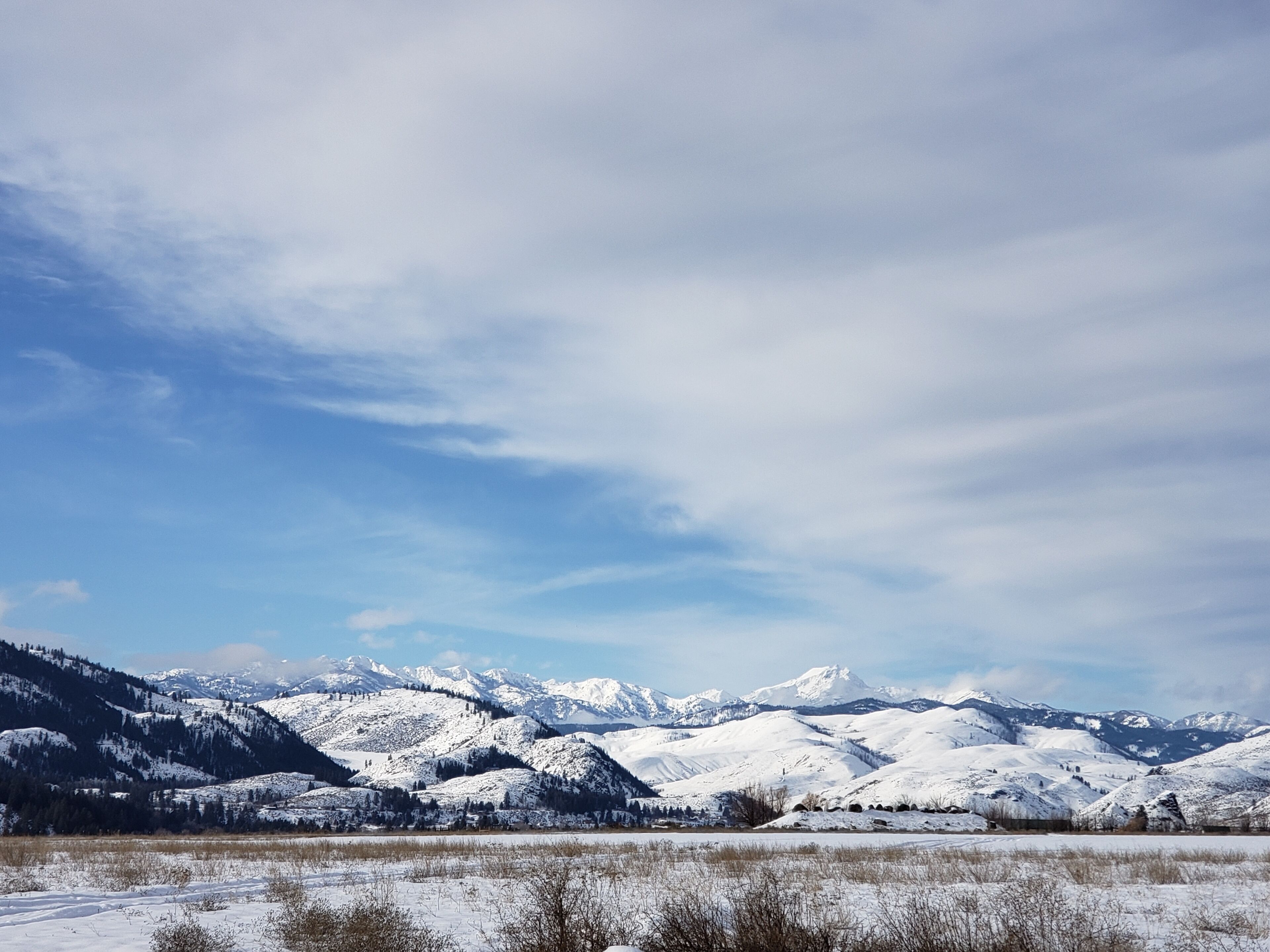 A panoramic view of a snow-covered mountainous landscape with a clear sky.