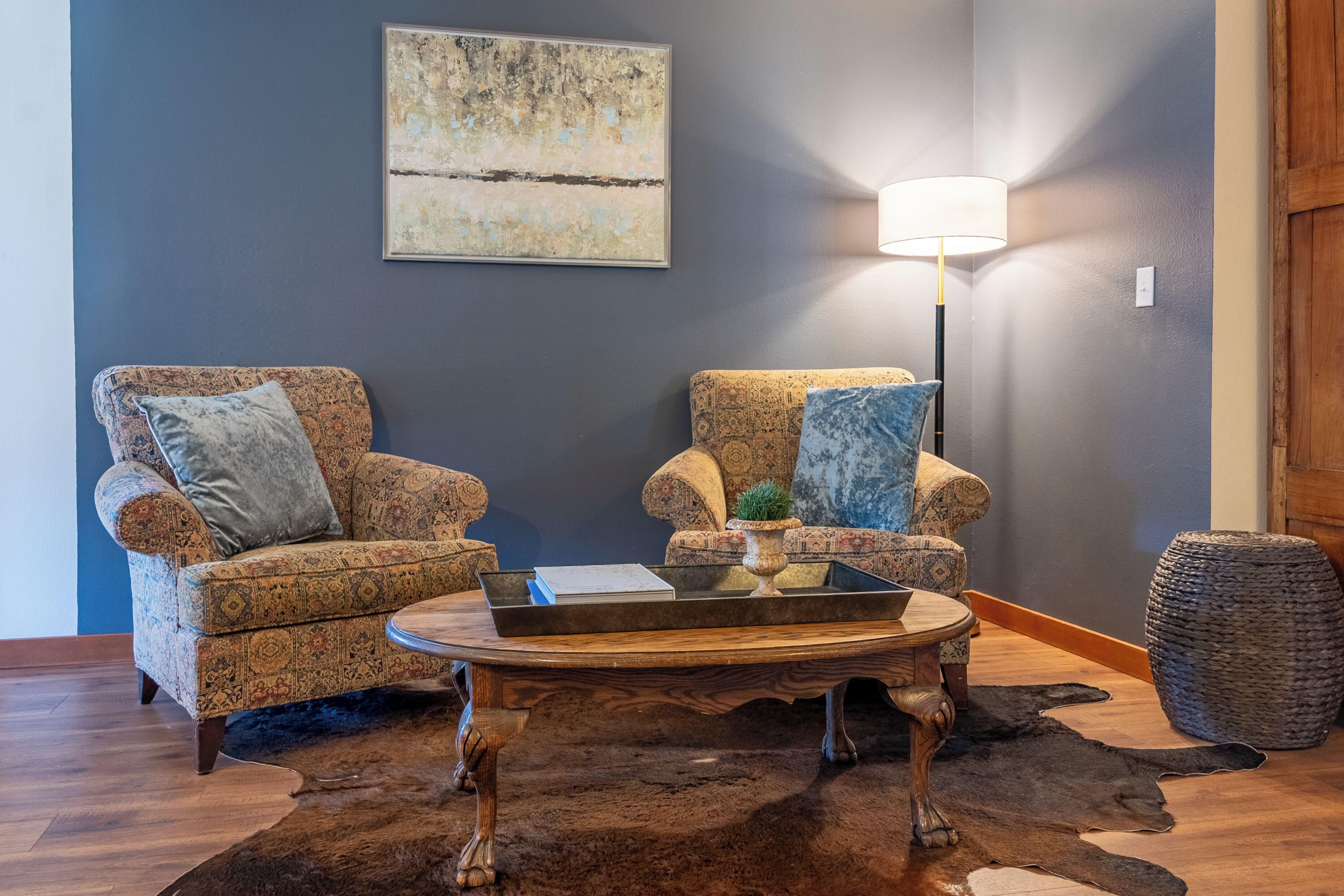 A living room with two patterned armchairs, a coffee table, a lamp, and a rug.