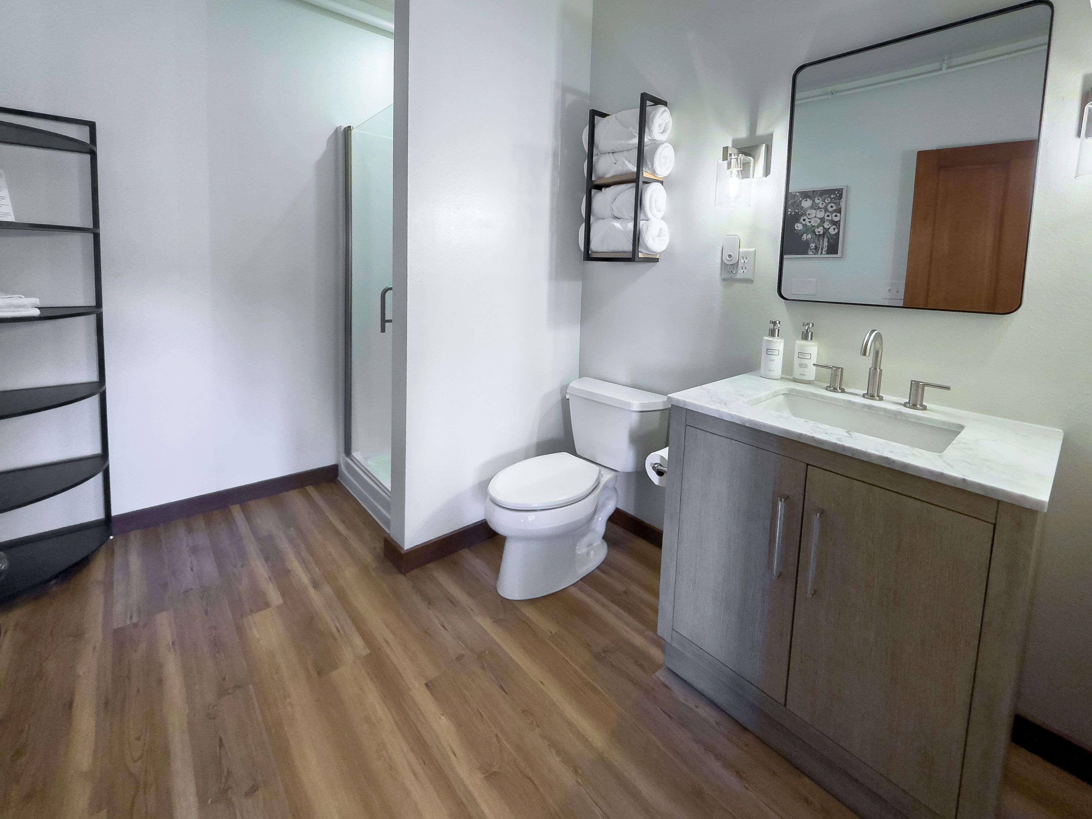 A bathroom with a toilet, a sink, a mirror, and a glass shower enclosure.
