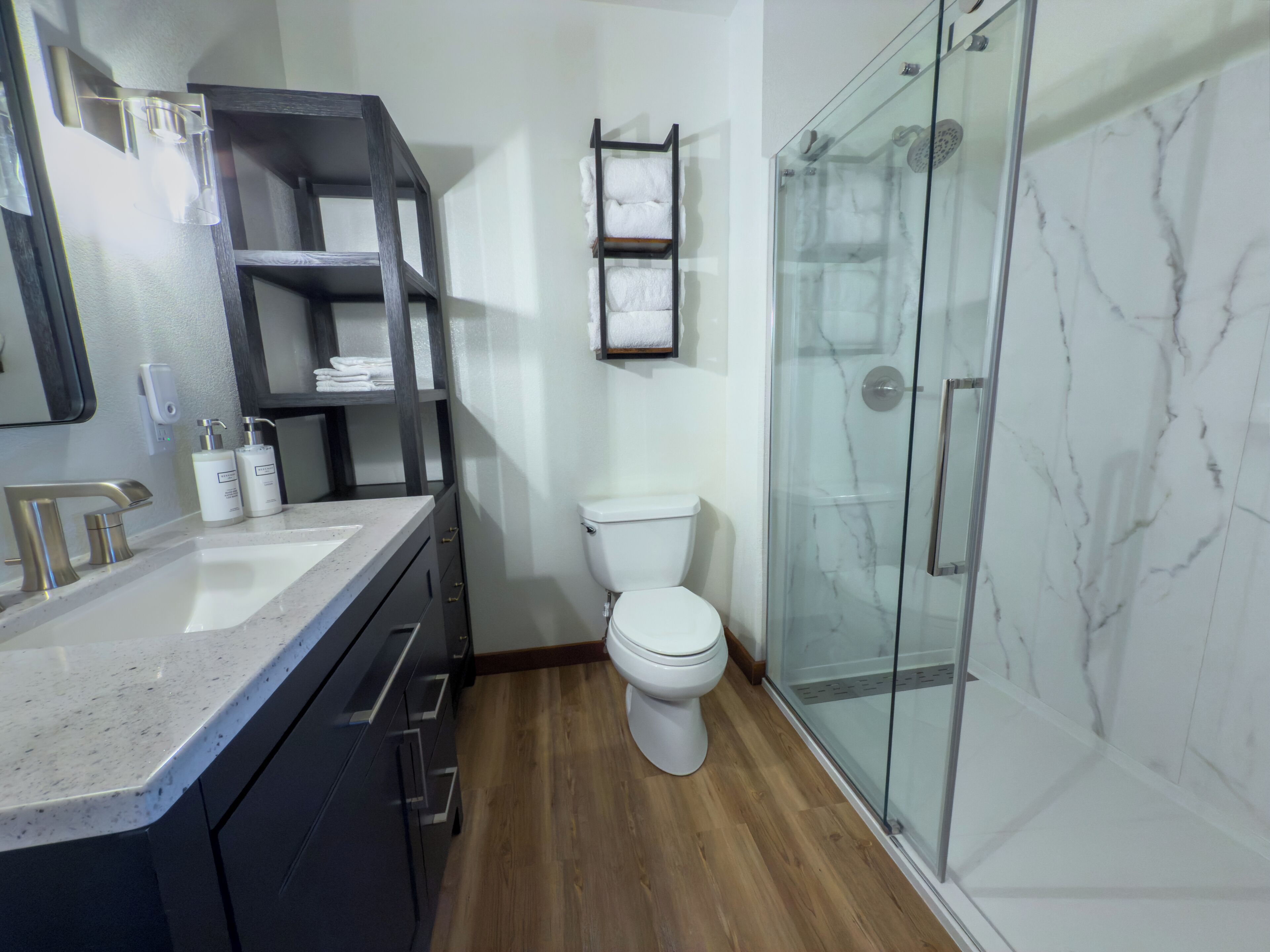A modern bathroom with a glass shower enclosure, a toilet, and a vanity with a sink.