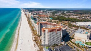 A coastal cityscape with a beach, a large hotel named Pineapple Willy's, and surrounding buildings. - Shores of Panama 926- Free Beach Chairs! (Panama City Beach)
