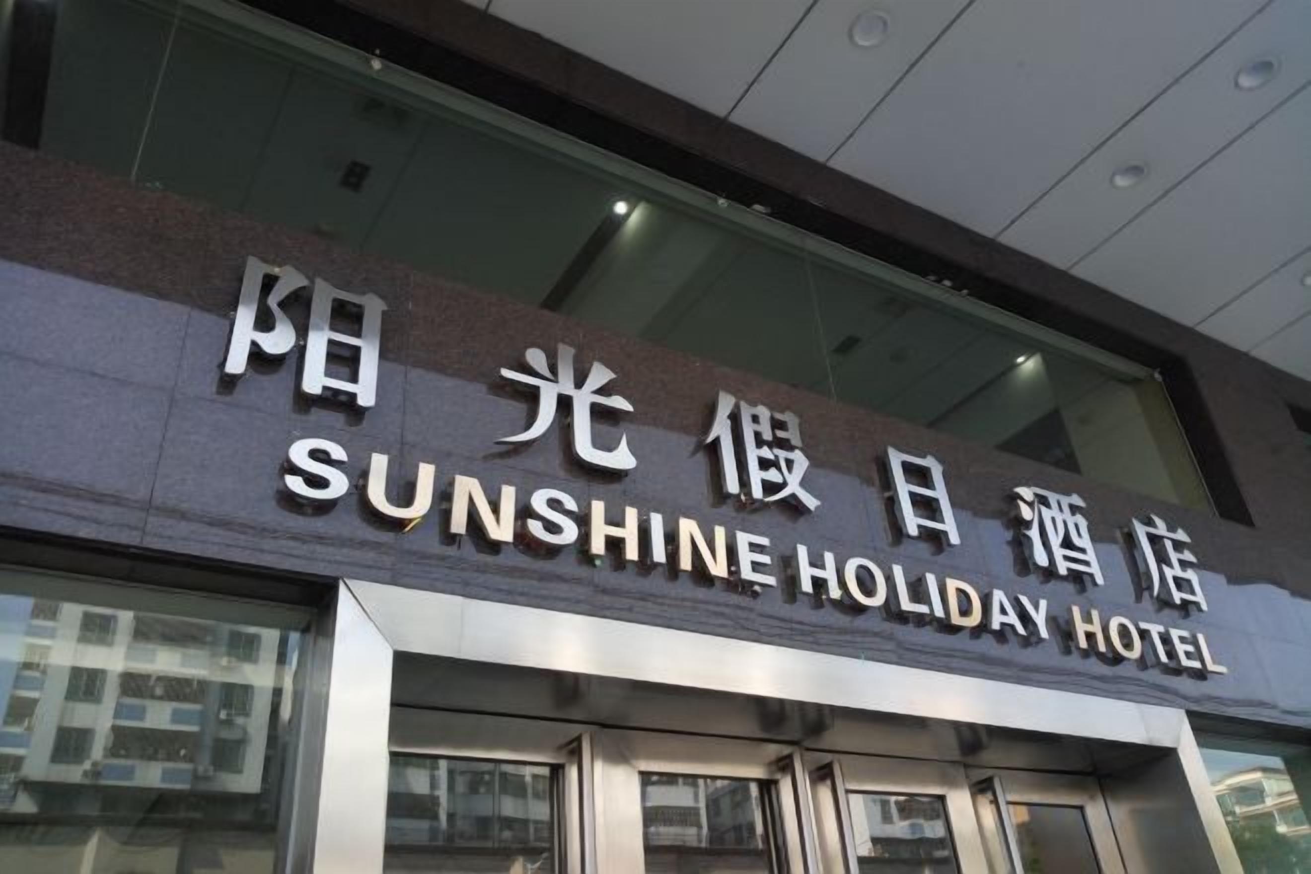 Het uiterlijk van Hotel Sunshine Holiday, met een opvallend bord en de ingang.