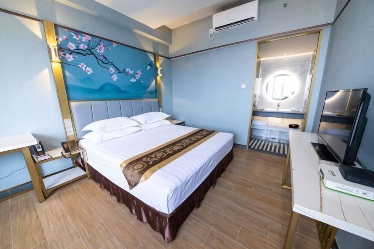 Una habitación de hotel con cama, mesita de noche, escritorio y televisor.