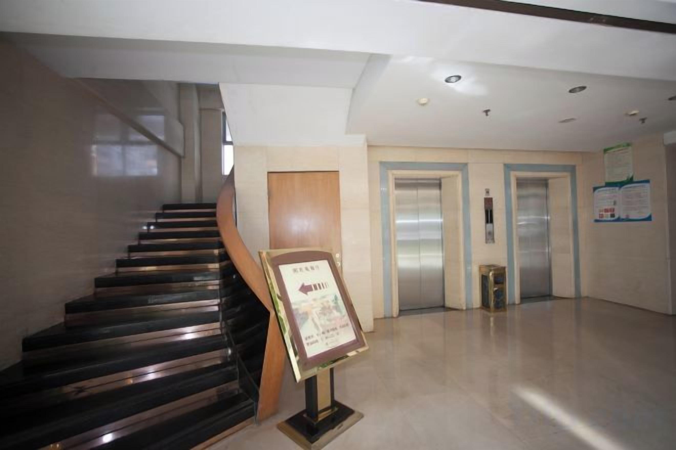 A staircase leading to an elevator, a bulletin board, and a clean, modern interior with a polished floor.
