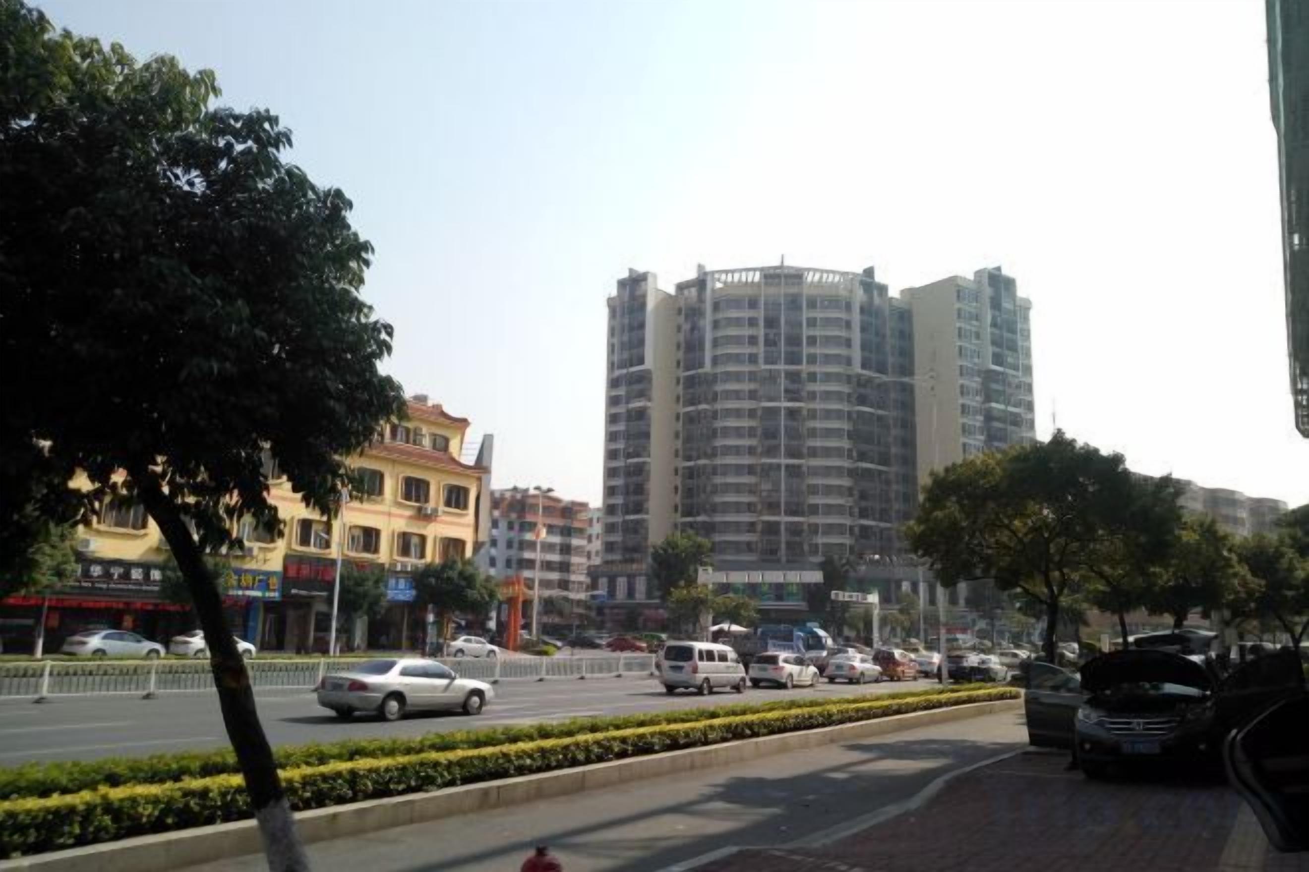 A street view with a multi-story building, vehicles, and a sidewalk.