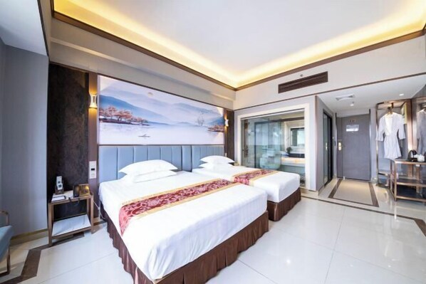 Une chambre d’hôtel moderne avec deux lits, une grande fenêtre et une vue sur un paysage enneigé.