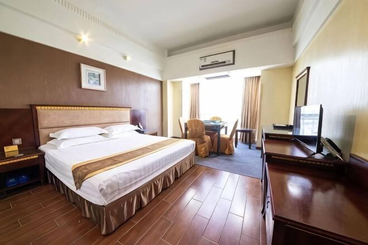 Una habitación de hotel con una cama grande, un escritorio, una silla y un televisor.