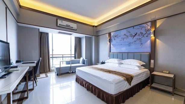 A modern hotel room with a large bed, a desk, and a window with curtains. - Sanshui Sunshine Holiday Hotel (Foshan)