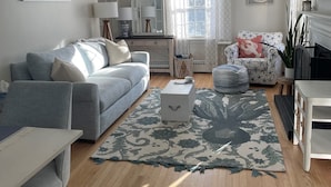 A living room with a grey sofa, a patterned rug, and a white coffee table. - Adorable, Bright and By the Bay! (Falmouth)