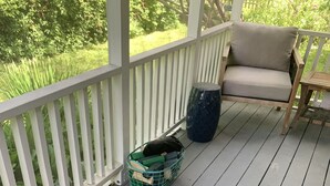 A wooden deck with a white railing, a beige chair, a small table, and a green basket. - Adorable, Bright and By the Bay! (Falmouth)