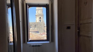A room with a view of a historic building through a window, a radiator, and a wooden door. - San Placido Inn (Catania)