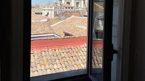 A view through a window of a building with a dome structure in the background, a tiled roof, and a clear sky. - San Placido Inn (Catania)