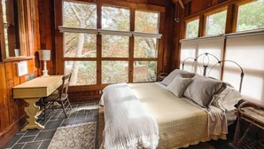 Ein gemütliches Schlafzimmer in einer Blockhütte mit Bett, Schreibtisch und Stuhl.