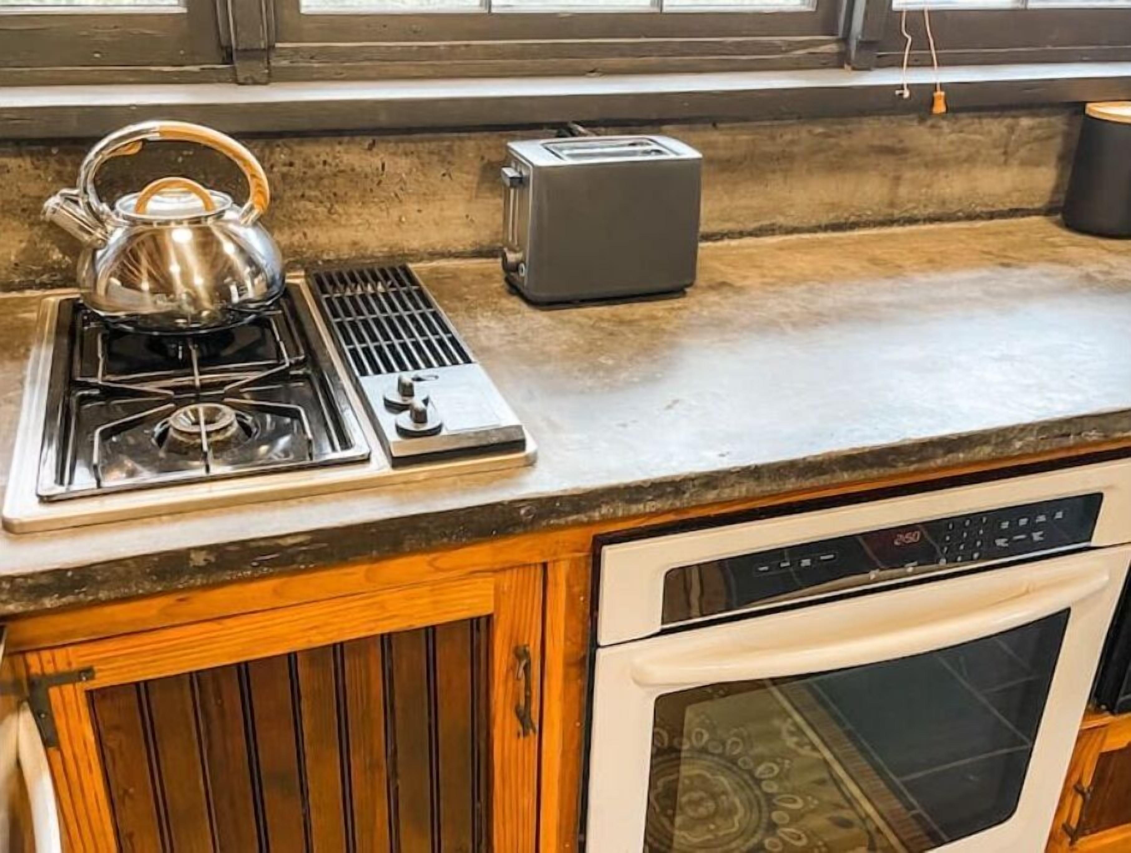 Een keuken met een gasfornuis, waterkoker, broodrooster en vaatwasser.