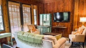 Ein gemütliches Wohnzimmer mit einer Couch, Sesseln, einem Fernseher und einem kleinen Tisch.