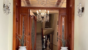 A grand entrance with a wooden door, a chandelier, and two large vases. - Luxurious Boutique Palace in the heart of Condesa (Ciudad de México)