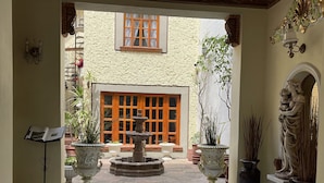 A spacious lobby with a tiled floor, a central fountain, and potted plants. - Luxurious Boutique Palace in the heart of Condesa (Ciudad de México)