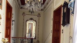 A grand hallway with a marble floor, a large ornate mirror, a chandelier, and a wooden desk with a brass candelabra. - Luxurious Boutique Palace in the heart of Condesa (Ciudad de México)