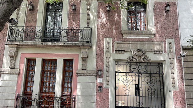 A building with a pink facade, ornate iron gates, and a balcony with a wrought iron railing. - Luxurious Boutique Palace in the heart of Condesa (Ciudad de México)