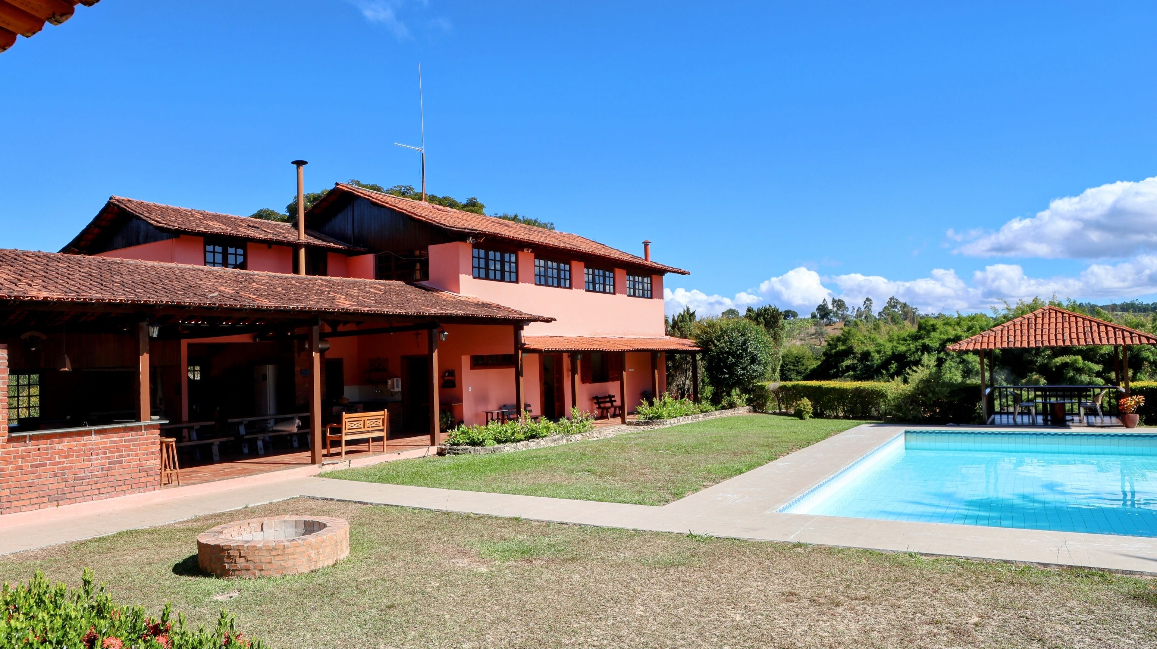 A two-story building with a swimming pool, outdoor seating, and a fire pit.