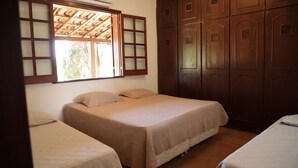 Een kamer met twee bedden, een houten garderobe en een raam met houten kader.