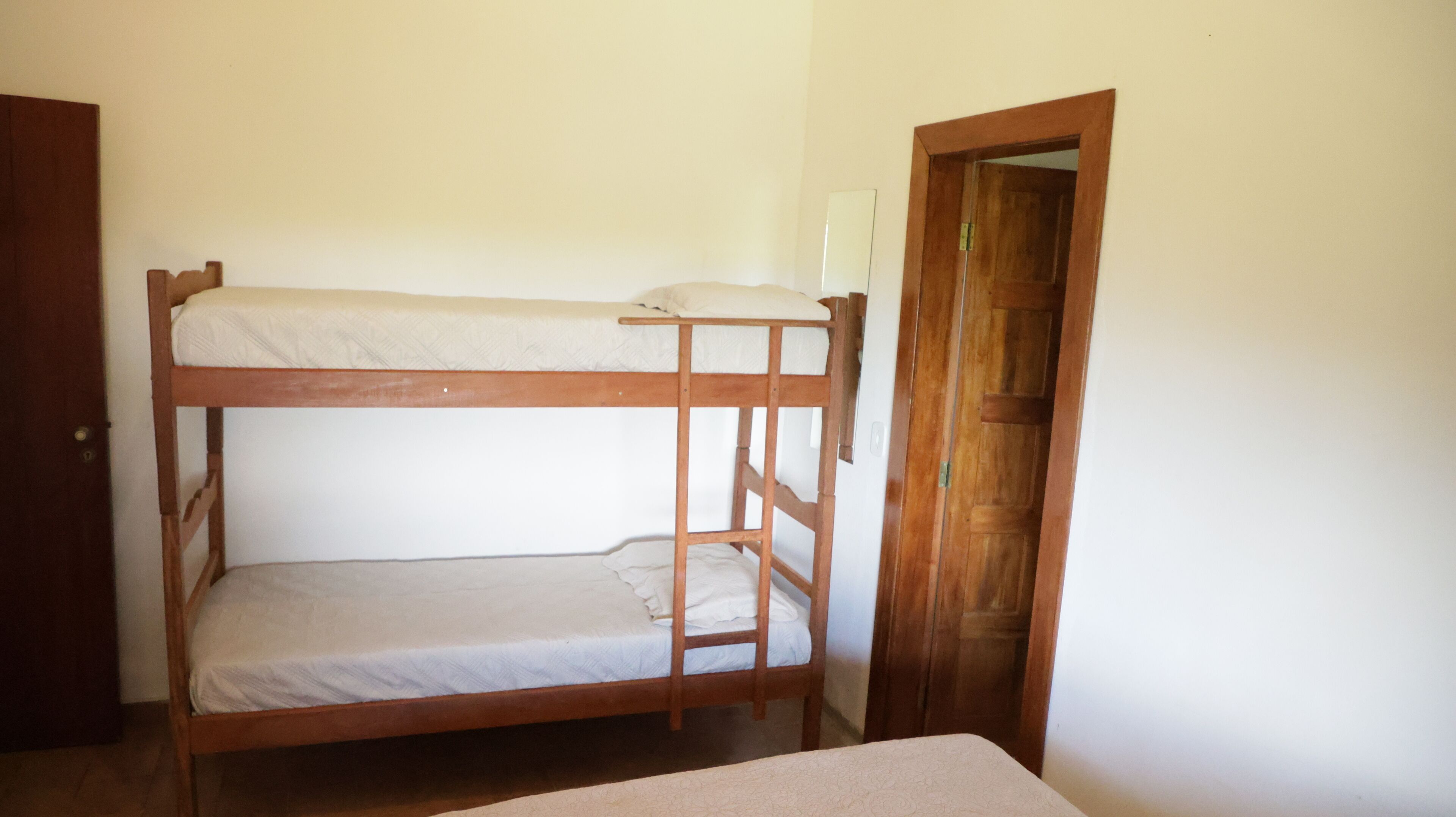 Una cama litera de dos plazas, una puerta de madera y una pared blanca.