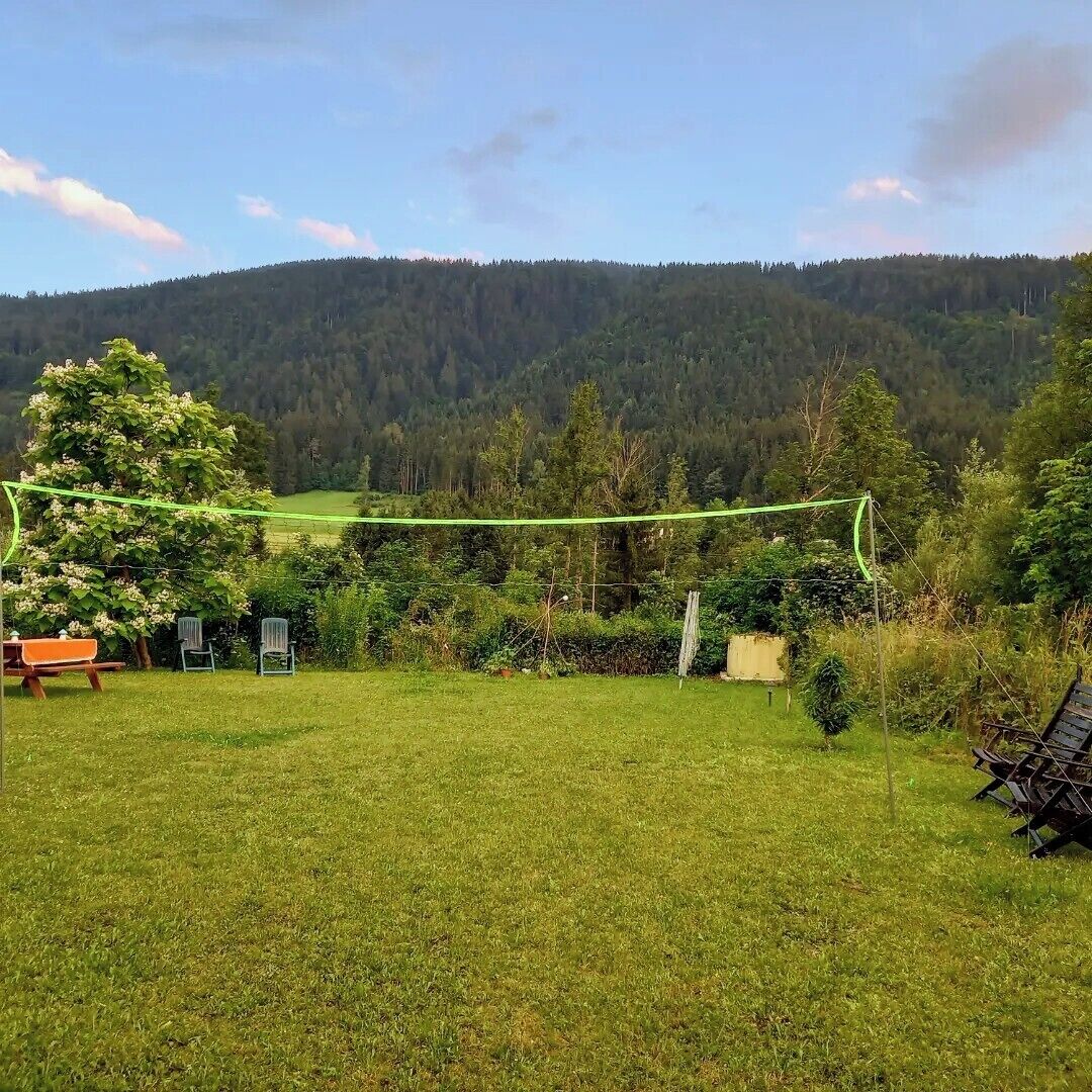 A grassy outdoor area with a bench, chairs, and a tree.