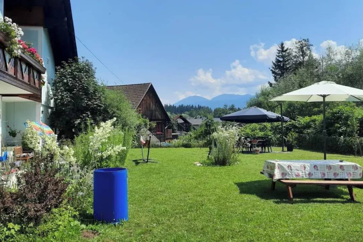 A well-maintained garden with a lawn, a picnic table, and a blue barrel.