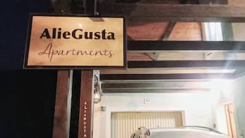 Señalización para 'AlieGusta Apartments' con el número '58' en la entrada de un edificio.
