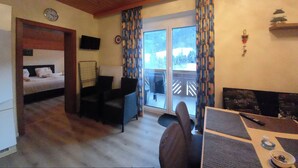 A room with a bed, a sofa, a small table, a chair, a TV, and a window with curtains. - Aliegusta (Gitschtal)