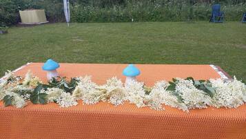 A table with a crocheted orange tablecloth, two blue mushroom-shaped candle holders, and white flowers.