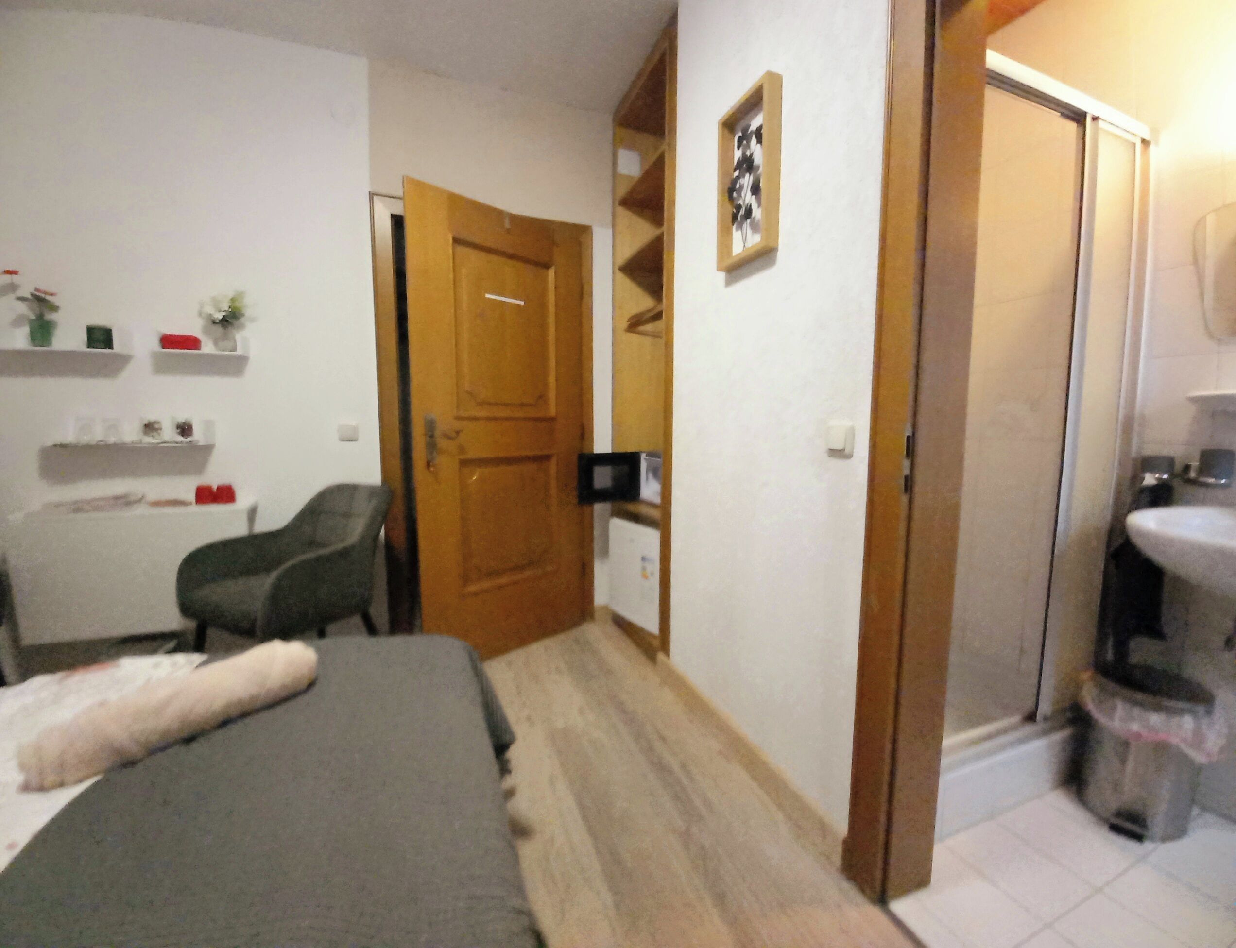 A bedroom with a bed, a desk, a chair, a wardrobe, and a bathroom.
