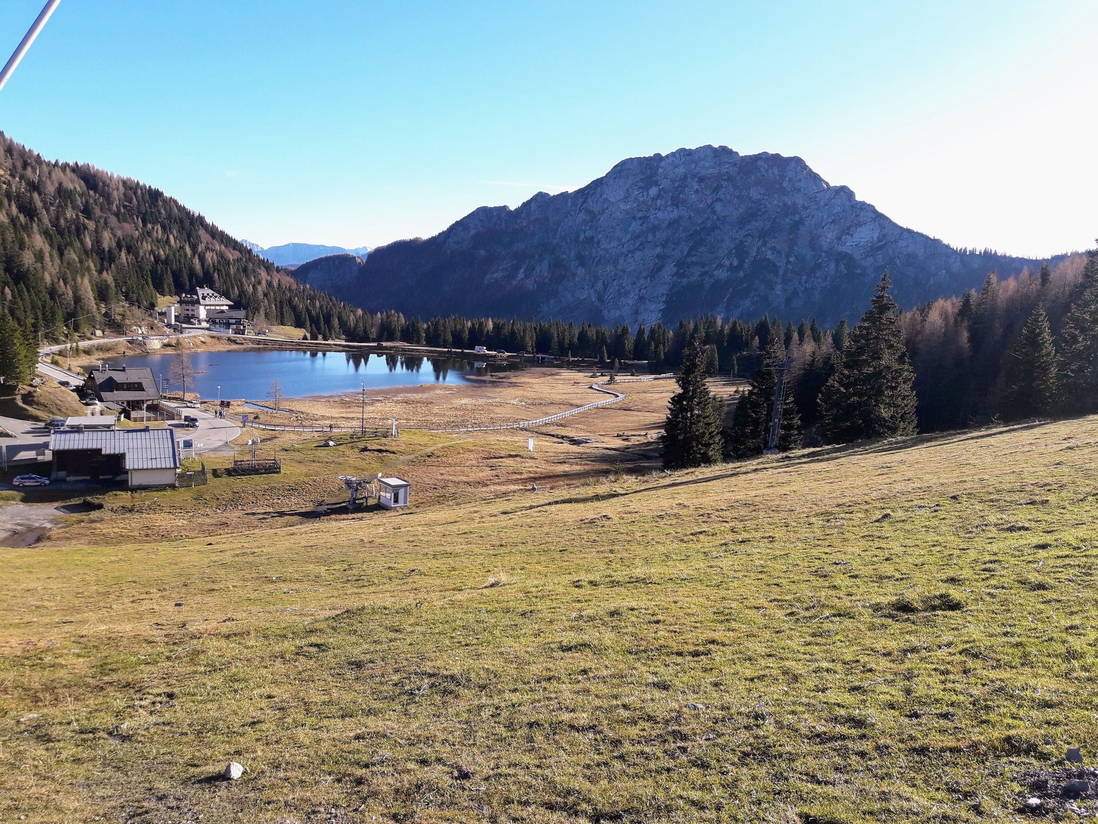 Eine Berglandschaft mit einem See, einem kleinen Gebäude und einer Straße.