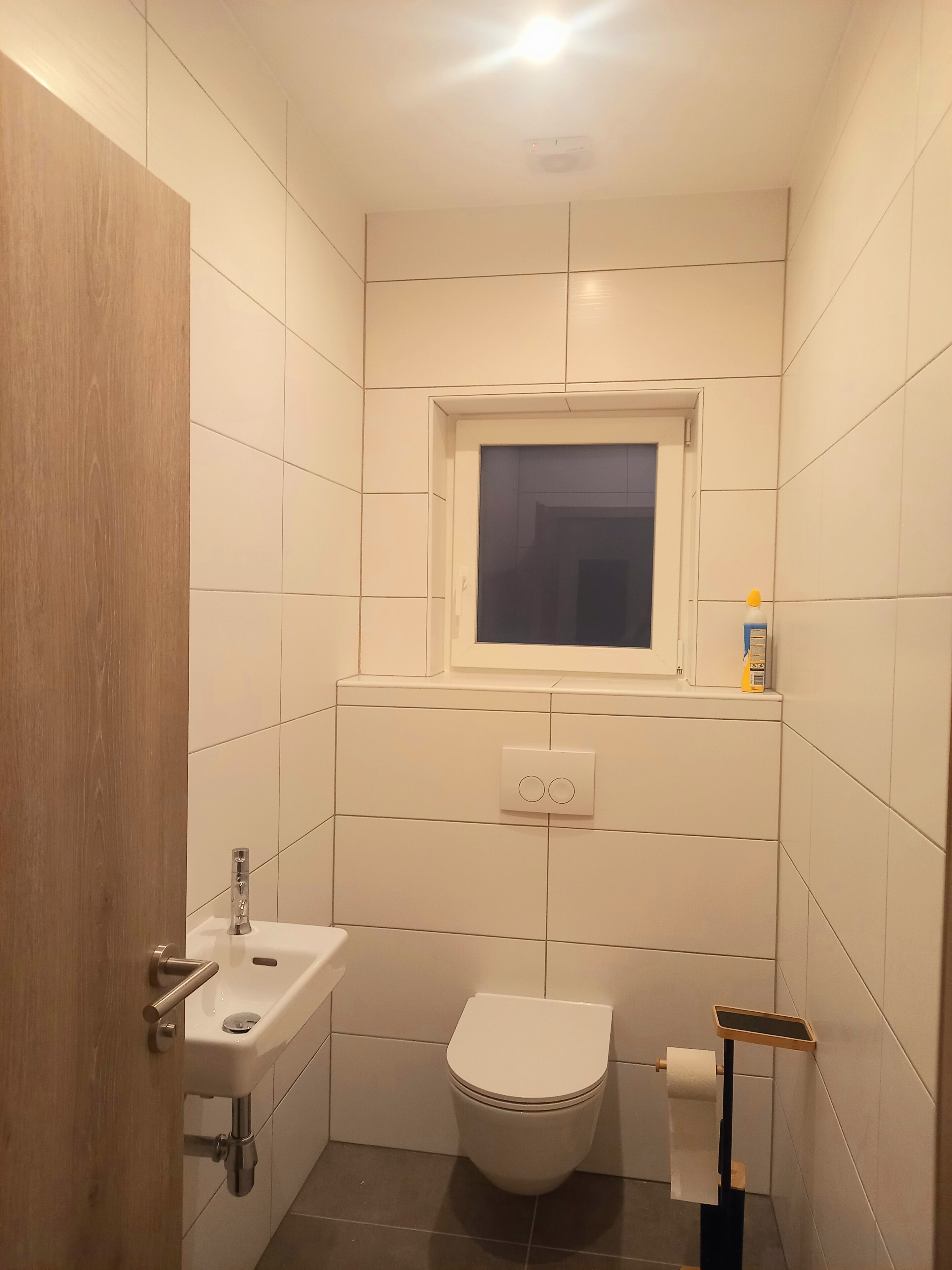 Une petite salle de bain propre, équipée de toilettes, d’un lavabo et d’une fenêtre.